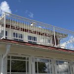 Specialbyggt balkongräcke i smide som harmonierar med husets klassiska arkitektur och vita detaljer. Vitt balkongräcke i smide monterat på villa i Rimforsa med varmförzinkad och pulverlackerad konstruktion.