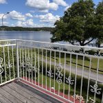 Smidesräcke B7c i vit RAL 9010 som ger en elegant inramning av balkongen och utsikten över sjön. Balkongräcke i smide B7c med vit pulverlack och dekorativa detaljer på balkong med sjöutsikt.