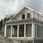 Smidesräcke B6 med raka spjälor runt balkongen, tillverkat efter kundens mått och pulverlackerat i svart ultramatt. Svart smidesräcke runt balkong på vit villa i Stenungsund, modell B6 med raka spjälor och måttanpassade sektioner.